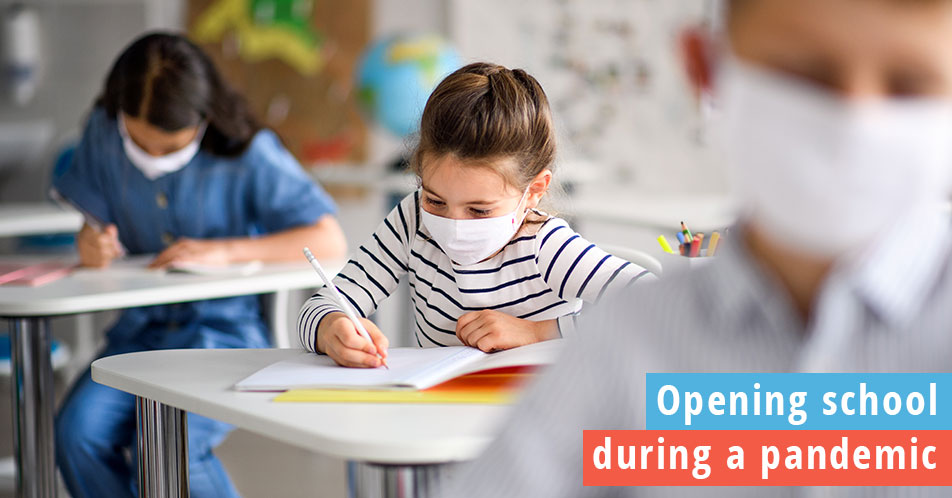 Opening schools during a pandemic, students in masks socially distanced in a fully opened school